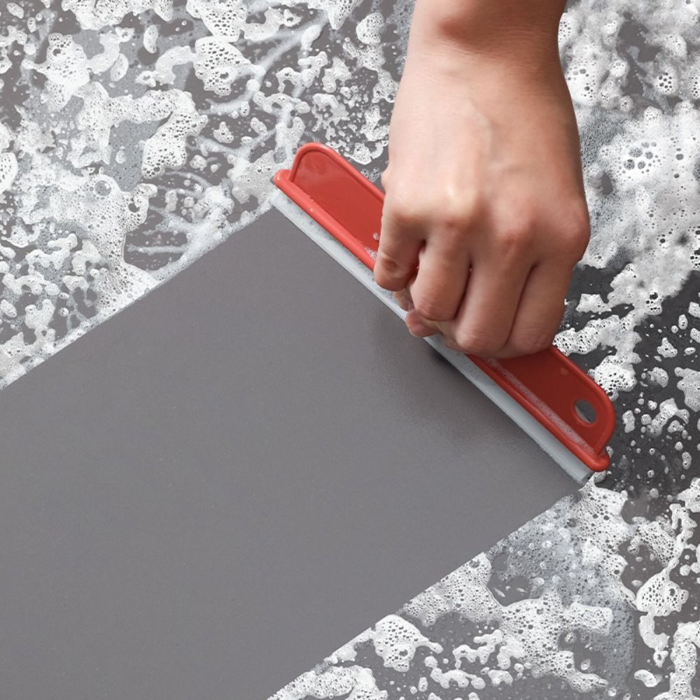 a person using a squeegee to remove a grey surface